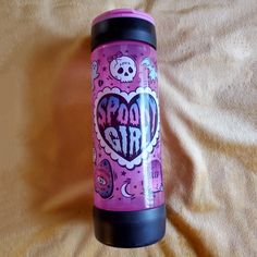 a pink and black travel mug with the words spook girl written in it on a yellow blanket