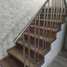 a set of wooden stairs with metal handrails in a room next to a brick wall