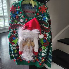 an ugly sweater with a santa clause on it and a doll hanging from the back