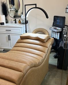 a tan leather chaise lounge in front of a desk with a laptop on it