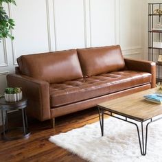 a brown leather couch sitting on top of a wooden floor next to a coffee table