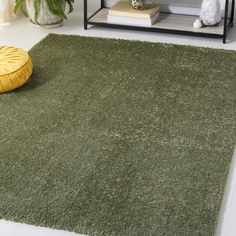 a green rug in a living room next to a yellow bean bag chair and coffee table