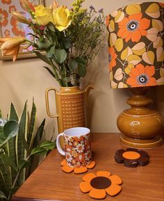 a vase with flowers and two matching coasters on a table next to a lamp