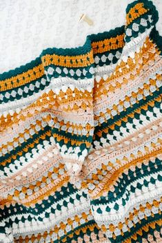 a crocheted blanket laying on top of a bed next to a white wall