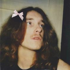 a man with long hair wearing a pink bow