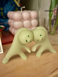 two plastic ghost figurines sitting on top of a wooden table