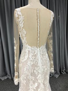 the back of a white wedding dress with long sleeves and beaded details on it