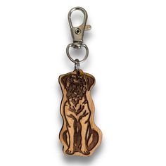 a wooden key chain with a dog on it's front and back ends, hanging from a metal hook