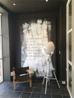 a chair and lamp in front of a black wall with words on the wall behind it