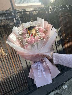 a person holding a bouquet of flowers in front of a gate with a bird on it