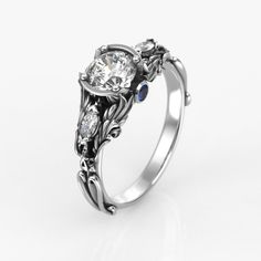 a white gold engagement ring with two diamonds and blue sapphire stones on the sides, set in