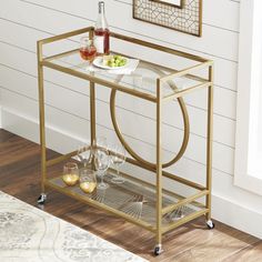 a gold bar cart with wine glasses and fruit on it