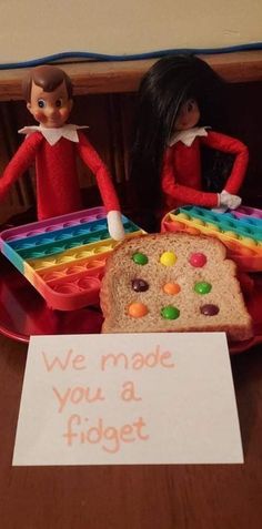 two elfs are sitting on a table with bread and candy