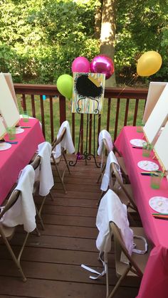 tables set up with pink and white tablecloths for a birthday party on a deck