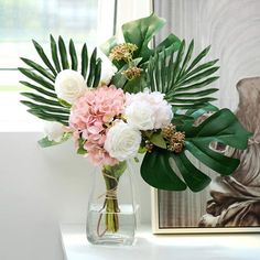 a vase filled with pink and white flowers on top of a table next to a painting