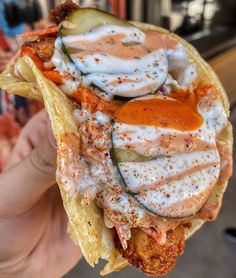 a person holding up a taco filled with sauce and vegetables