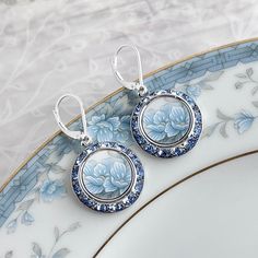 Beautiful and romantic, our handmade china earrings are artfully repurposed from a vintage china plate, surrounded in brilliant light blue sapphire crystals from Europe.  .75" round. Top to bottom is 1.5". Sterling silver hinged lever back ear wires,  Mixed metal settings with a real rhodium finish to prevent tarnishing. DinnerWear Jewelry® ~ Specializing in one of a kind pieces since 1998. Our individually hand crafted pieces are 100% guaranteed. SHIPPING : Free shipping to USA for jewelry. We 20th Anniversary Gifts, Light Blue Sapphire, Broken China Jewelry, Porcelain Earrings, Flower Crystal, China Jewelry, Broken China, Jewelry Statement, Anniversary Gifts For Wife