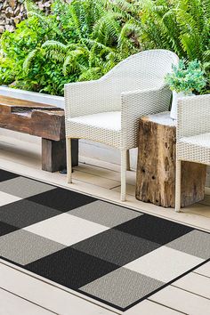 two white chairs sitting on top of a wooden floor next to a blue and white rug