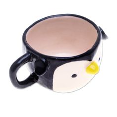 a black and white penguin coffee cup with yellow beaks on it's face