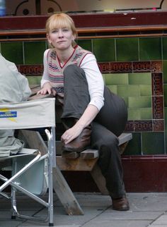 a woman sitting on top of a wooden bench