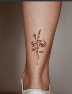 a woman's foot with a flower tattoo on the side of her leg,