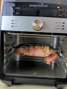 a piece of meat is being cooked in an open toaster oven on a counter