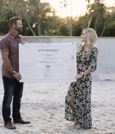 a man standing next to a woman holding a large check