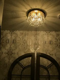 a chandelier hanging from the ceiling in a room with marble walls and doors