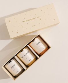 three candles in a gift box on a white surface with an inscription above the candle