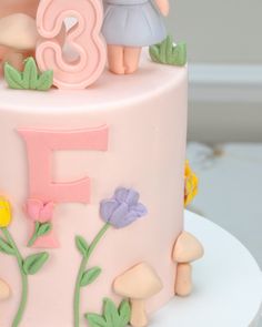 there is a pink cake decorated with flowers and the number five on it's side