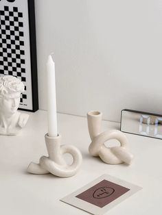 two white candles sitting on top of a table next to a mirror and vases