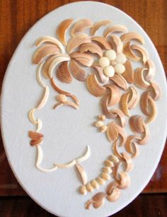 a white plate topped with shells and flowers on top of a wooden table next to a wall