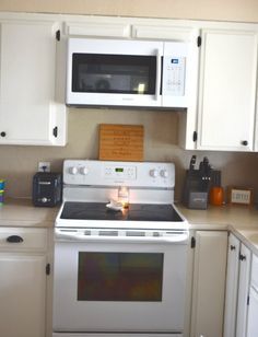 a white stove top oven sitting inside of a kitchen next to microwaves and cabinets