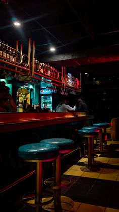 a dimly lit bar with stools in front of it