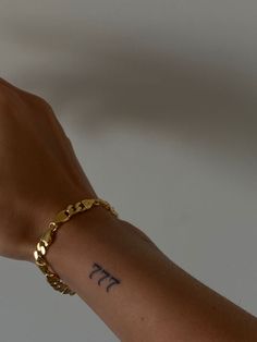 a person's arm with a tattoo on it and a gold chain around the wrist