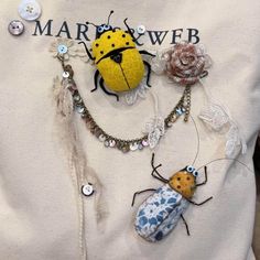 a ladybug and insect brooch on a white shirt with words mary webb