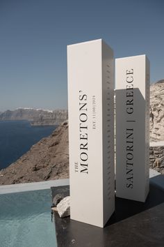 two white boxes sitting next to each other on top of a black table near the ocean