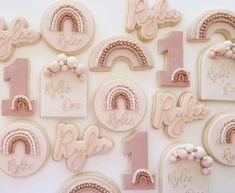 cookies decorated with pink icing and white frosting are arranged in the shape of rainbows