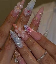 a woman's hand with pink and white nail polishes on her nails, decorated with flowers