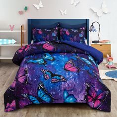 a bed with purple and blue butterflies on the comforter, next to a night sky background