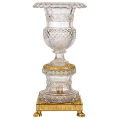 an ornate glass vase sitting on top of a wooden stand with gold trimmings