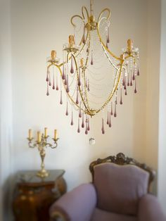 a chandelier hanging from the ceiling in a room with purple chairs and a table