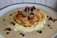 a white plate topped with mashed potatoes covered in gravy and pecans