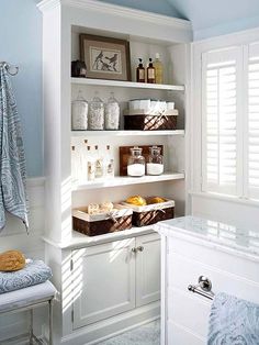 a bathroom with blue walls and white shelves filled with bath products, towels, and other items