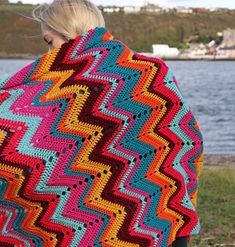 a woman wearing a multicolored crocheted blanket