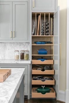 a kitchen with gray cabinets and white marble counter tops, open shelving unit in the middle