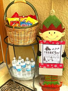 a elf holding a thank you sign next to a basket with candy and water bottles