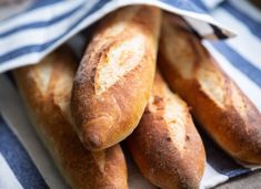 several loaves of bread sitting on top of a blue and white striped cloth,