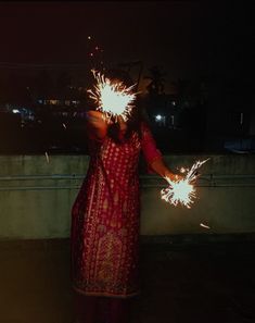 a woman holding sparklers in her hands at night