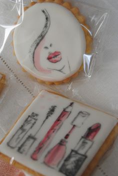 some cookies with designs on them are sitting on a white tablecloth and one is decorated like a woman's face